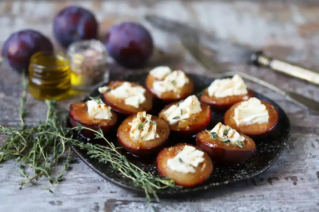 Assiette de prunes rôties servies avec du fromage feta